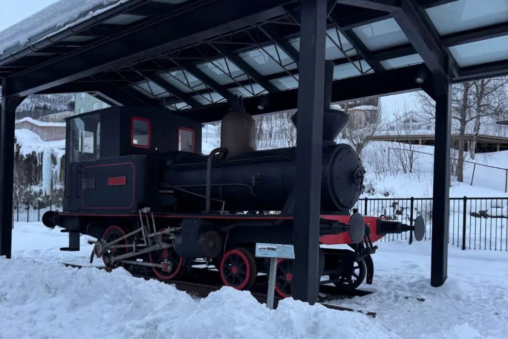 Old steam locomotive on display under a snowy roof at Narvik train station in February