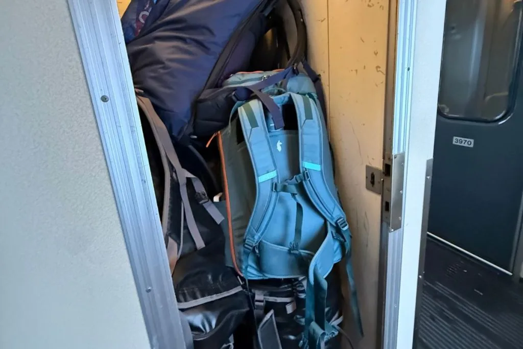 Hiking backpacks stacked in an open, doorless luggage locker at the end of an SJ night train car