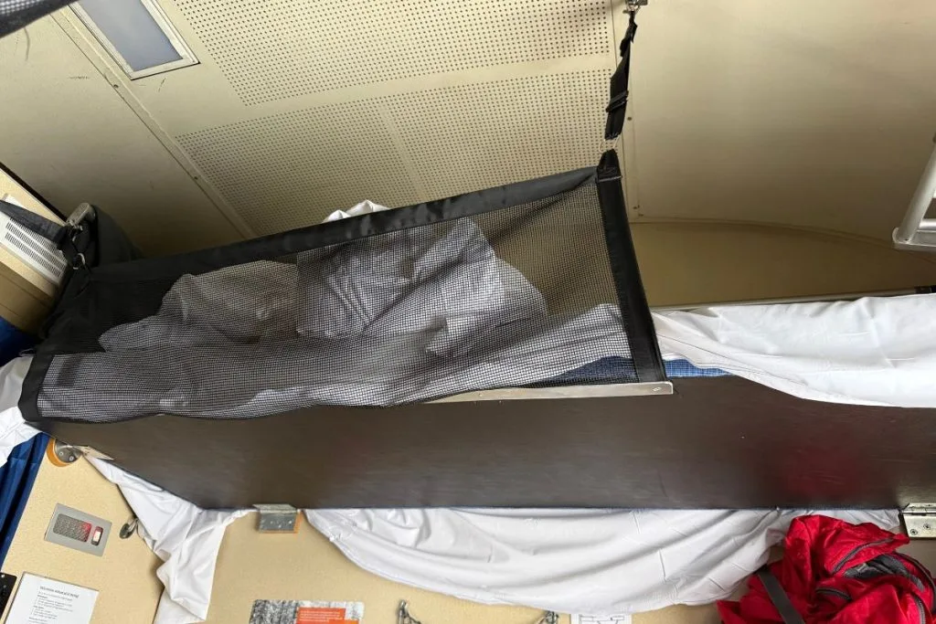 Safety net on the top bunk of a sleeper train couchette, seen from the bunk below