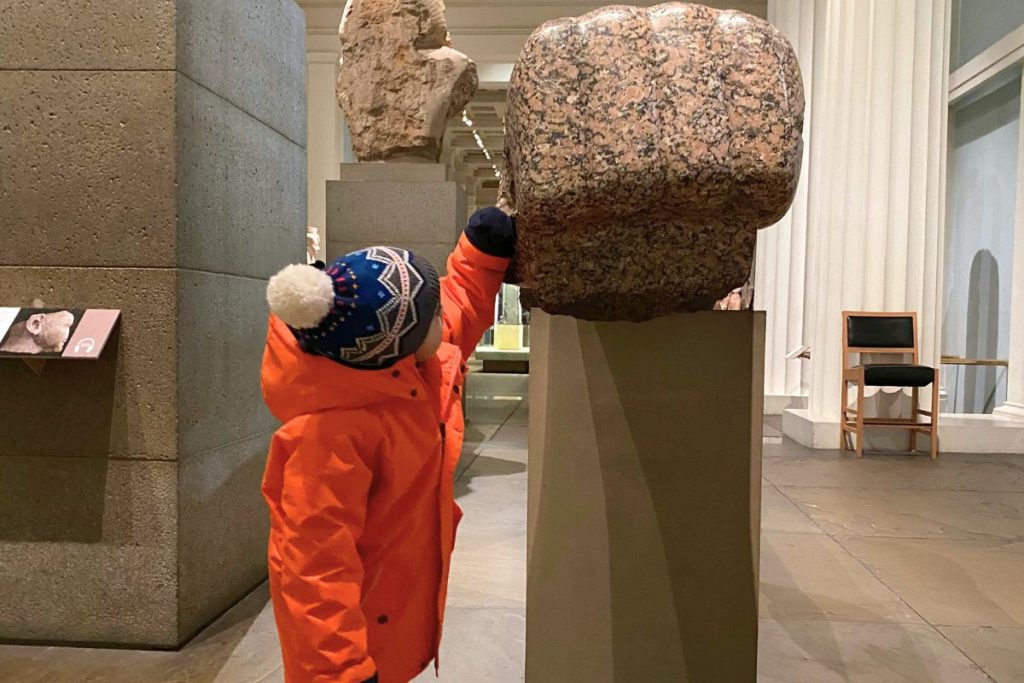 4-year-old fist bumping Egyptian sculpture at British Museum - free attraction perfect for 2 days in London with kids