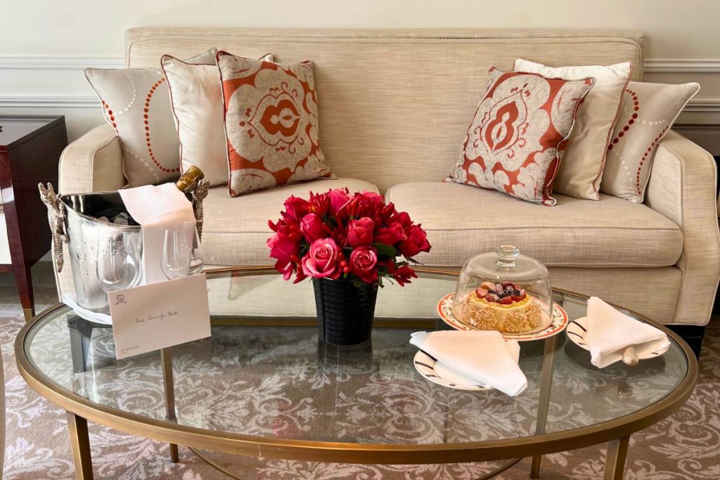 St. Regis Rome suite living room with couch, desk, TV, bar area, and pocket door separating bedroom