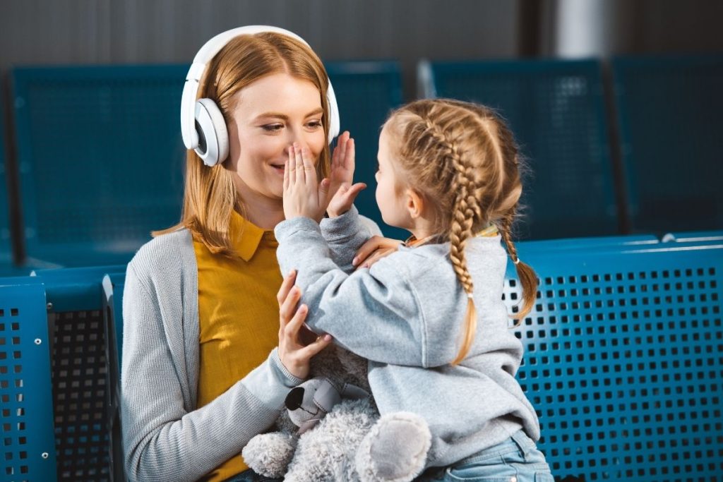 Parent wearing noise-canceling headphones on flight with twins for mental health break