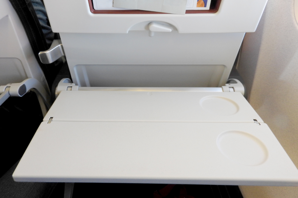 Baby playing with airplane tray table latch — free entertainment for infants on planes